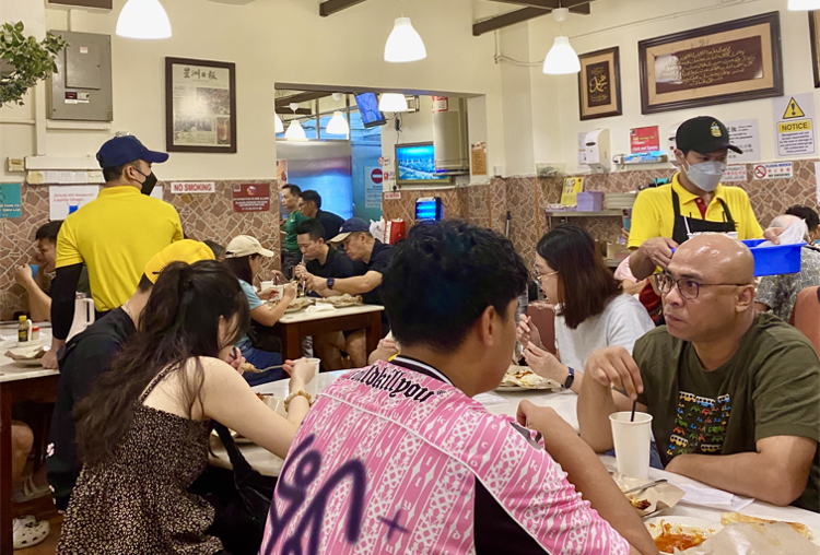 Staff serving customers at crowded tables inside Village Park Restaurant