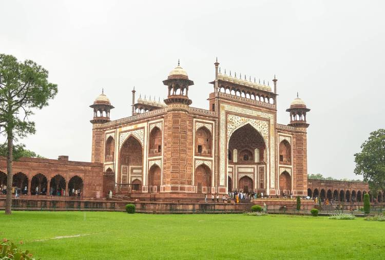 Red sandstone gate of the Taj Mahal complex across the green lawn