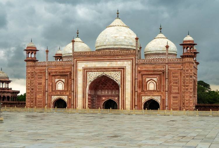 Red sandstone mosque with white domes beside the Taj Mahal