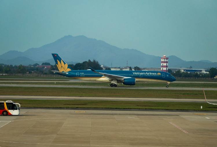 Vietnam Airlines plane on the runway at Hanoi airport with mountains behind