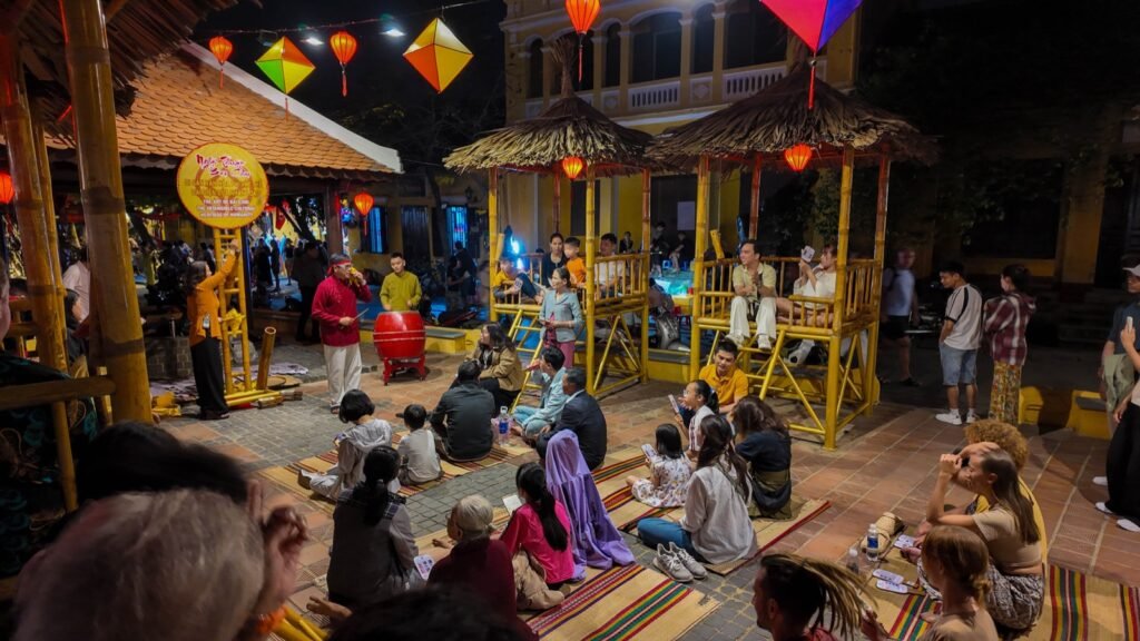People watching a traditional performance on a Hoi An street at night