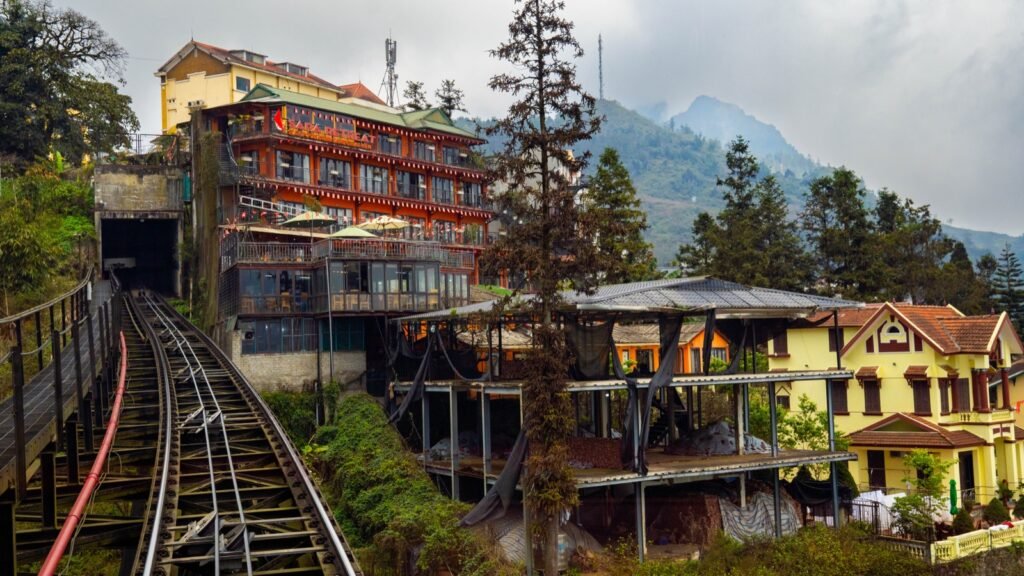 Old buildings and the mountain railway in Sapa with misty peaks behind
